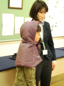 複製の防空頭巾をかぶってみる児童